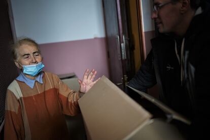 Ana, de 82 años, recibe comida en su casa del centro de Kiev de manos de Vladímir, un conductor voluntario que la recoge en un restaurante y la reparte a personas que necesitan ayuda