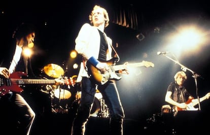 Mark Knopfler, en el centro, con su guitarra Fender y sus muñequeras, al frente de Dire Straits.