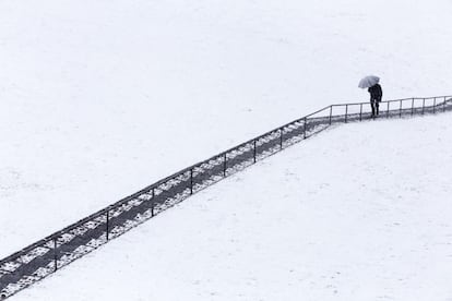 Un hombre sube unas escaleras bajo una intensa nevada caída en Ávila.