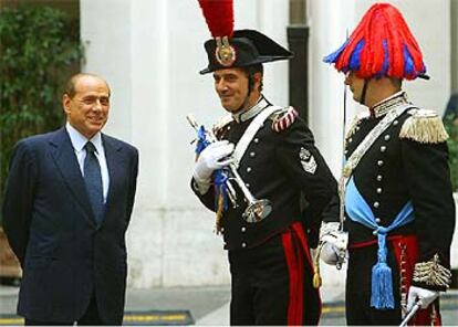 Berlusconi charla con dos <i>carabinieri</i> en traje de gala mientras espera a Abdalá de Jordania, en Roma.