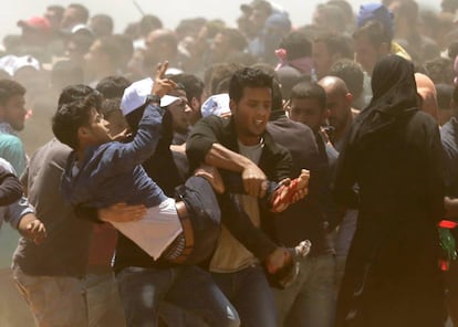 Várias pessoas ajudam a carregar um ferido durante o protesto na fronteira entre Gaza e Israel.