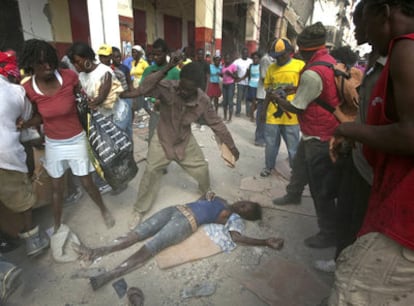 Una mujer yace en el suelo de una calle de Puerto Príncipe tras ser apaleada por una turba de saqueadores.