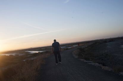 Durante el amanecer, un paseante avanza entre los esteros del Carrascón antes del despegue en San Fernando, Cádiz.