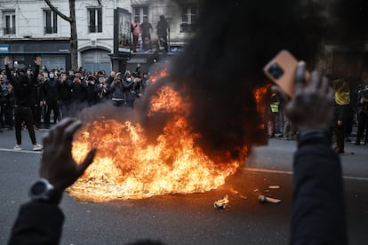 Varias personas se concentran frente a una hoguera, en una calle de París.