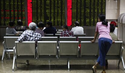 Varias personas comprueban la evolución de la bolsa de Shangái en Pekín (China).