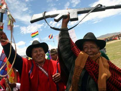 Dos miembros de los <i>ponchos rojos,</i> uno de ellos con un fusil simulado, vitorean al presidente Morales en Omasuyos.