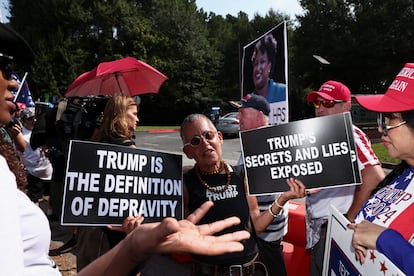An anti-Trump demonstrator holds banners next to supporters of former U.S. President Donald Trump near the entrance of the Fulton County Jail, in Atlanta, Georgia, on August 24, 2023.