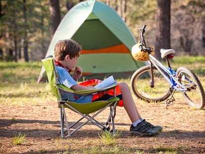 Un niño disfruta leyendo en un 'camping'.