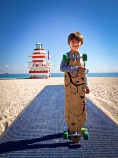 Un niño en la playa de Miami Beach, con la torre de vigilancia Jetty al fondo.