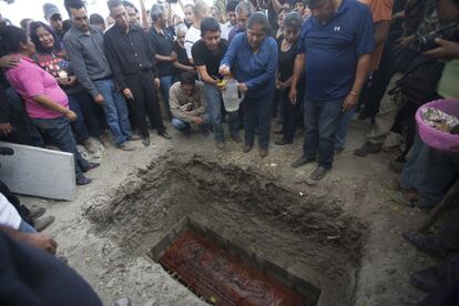 Juanita Ocampo deposita agua bendita en la tumba de su hija Gisela Mota, asesinada el 2 de enero en su domicilio de Temixco.