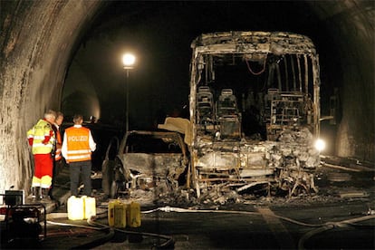 Varios agentes inspeccionan los restos calcinados de un coche y un autobús en el interior del tunel Viamala, cerca de Thusis, al sudeste de Suiza.