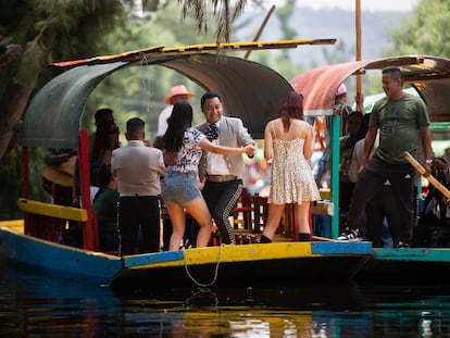 Un hombre vestido de mariachi baila con una turista a bordo de una trajinera en Xochimilco, en Ciudad de México, el 26 de abril de 2023.