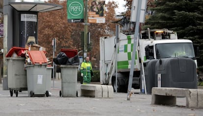 Un trabajador municipal junto a cubos de basura rebosantes en otoño de 2013.