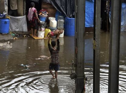 Un hombre carga a un bebé, por encima de su cabeza, mientras camina por una calle inundada tras las fuertes lluvias en Bombay (India), el 2 de julio de 2019. Las fuertes lluvias del monzón en el oeste de la India causaron que al menos tres paredes colapsaran en chozas y barracas de la ciudad. Según informes, se calcula que hasta el momento más de dos docenas de personas han fallecido.