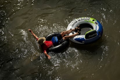 A tuber floats on the Comal River, July 26, 2023, in New Braunfels, Texas, as the area continues to feel the effects of triple-digit temperatures.