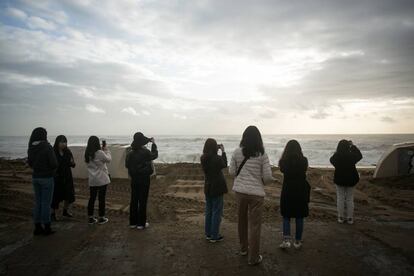 Un grup de turistes fan fotos a la platja de Barcelona, que ha quedat destrossada per l'onatge i la pluja.