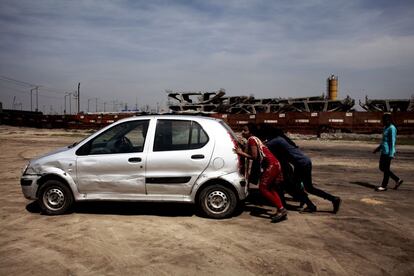 Algunas chicas empujan un coche que no funciona durante la practica de conducción en un descampado en el norte de Delhi.