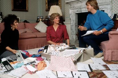 David y Elizabeth Emanuel con la princesa Diana mirando diseños y telas en su sala de estar del palacio de Kensington. Estaban planeando sus trajes para una próxima gira por los Estados del Golfo. 