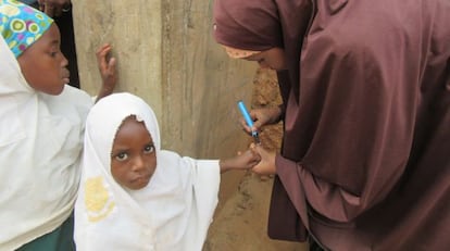 La pequeña Haguagua Abubacar, de 3 años, acaba de ser inmunizada en Dambatta y Muria Shehu le marca el dedo con un rotulador para evitar una doble vacunación.