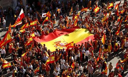 Manifestantes llevan una enorme bandera de España.