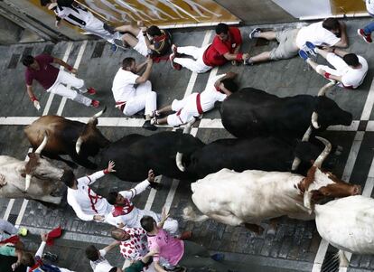 Los toros de Victoriano del Río Cortés enfilan la calle Estafeta junto a mansos y mozos durante el sexto encierro de los Sanfermines, el 12 de julio de 2018.
 