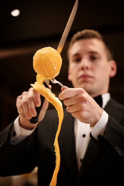 Un profesional de sala pela una naranja al estilo del restaurante Via Veneto, en Barcelona. Imagen proporcionada por el local.