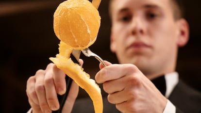 Un profesional de sala pela una naranja al estilo del restaurante Via Veneto.