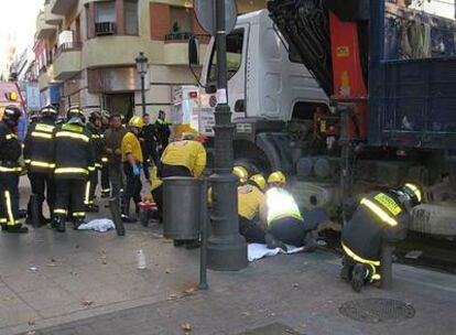 Los bomberos tratan de rescatar a la mujer, atrapada bajo el camión en Puente de Vallecas.