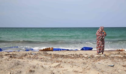 Un mujer permanece junto al mar en un punto de la playa donde quedan restos de barcas de madera y chalecos salvavidas en Sabrata, Libia.