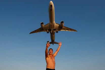 Un turista ruso se hace un selfi en la playa de Mai Khao mientras un avión despega del aeropuerto de Phuket, Tailandia.