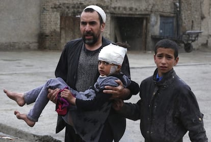 Un hombre lleva a una niña en brazos herida en un atentado cerca del Ministerio de Defensa en Kabul (Afganistán).