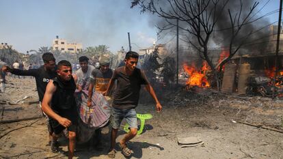 Un grupo de hombres trasladan a una de las personas alcanzadas por el bombardeo israelí en el campo de refugiados de Al Mawasi, en Jan Yunis (Gaza), este sábado.
