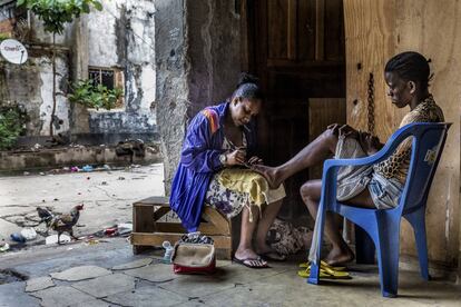 Ceia faz o pedicure de Alexandra. Favela da Mangueira, Rio de Janeiro. Das mulheres (das favelas) com trabalho remunerado, 44% tem emprego na economia formal.