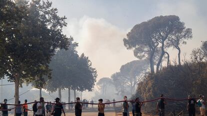 Vecinos y bomberos se afanan por apagar el incendio declarado esta tarde en el Paraje Natural de 'Las Canteras' en Puerto Real (Cádiz).