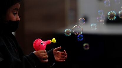 Una niña juega con una pistola de burbujas regalada por el personal de Migración luego de ser deportada con su familia desde Texas a Ciudad de Guatemala (Guatemala).
