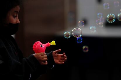 Una niña juega con una pistola de burbujas regalada por el personal de Migración luego de ser deportada con su familia desde Texas a Ciudad de Guatemala (Guatemala).