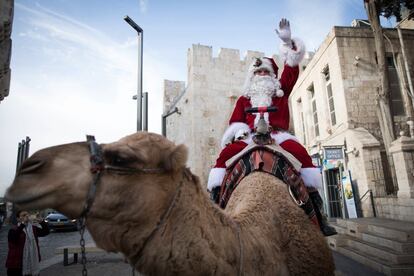 Papá Noel guía a su camello junto a las murallas de la antigua ciudad de Jerusalén, Israel.