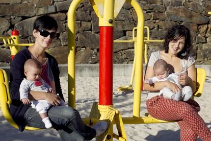 Beatriz Corredoira e Iria García, con sus mellizos en los brazos en un parque de Fene.