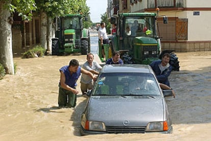 Un grupo de vecinos de Cortes (Navarra) retiran un vehículo en una de las calles inundadas por la tromba de lluvia.