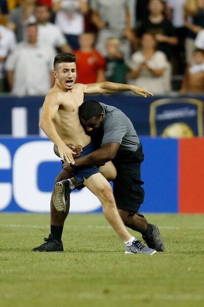 Un guardia de seguridad intenta parar a un fan que saltó al campo al finalizar el partido entre el Real Madrid y el París Saint-Germain.