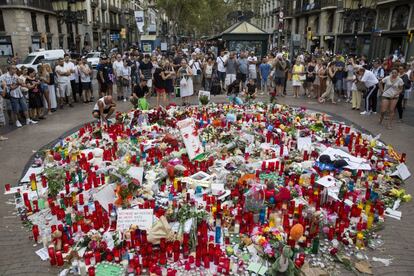 Turista y barceloneses frente a un altar improvisado en Las Ramblas de Barcelona, en homenaje a las víctimas del atentado.