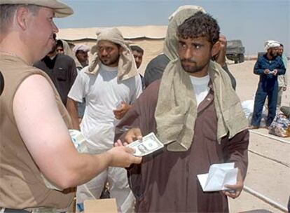 Un soldado de EE UU entrega 50 dólares a un prisionero iraquí liberado hoy en Camp Bucca.