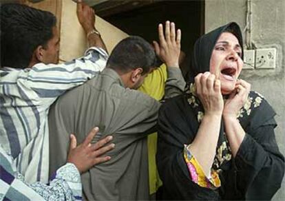 Una mujer iraquí llora desesperada mientras que unos hombres introducen cinco féretros en lo que fue su casa en un suburbio de Bagdad.