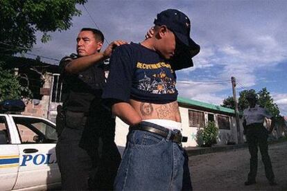 Un policía cachea a <i>El Manco, de la pandilla M-18</i>, en San Salvador.