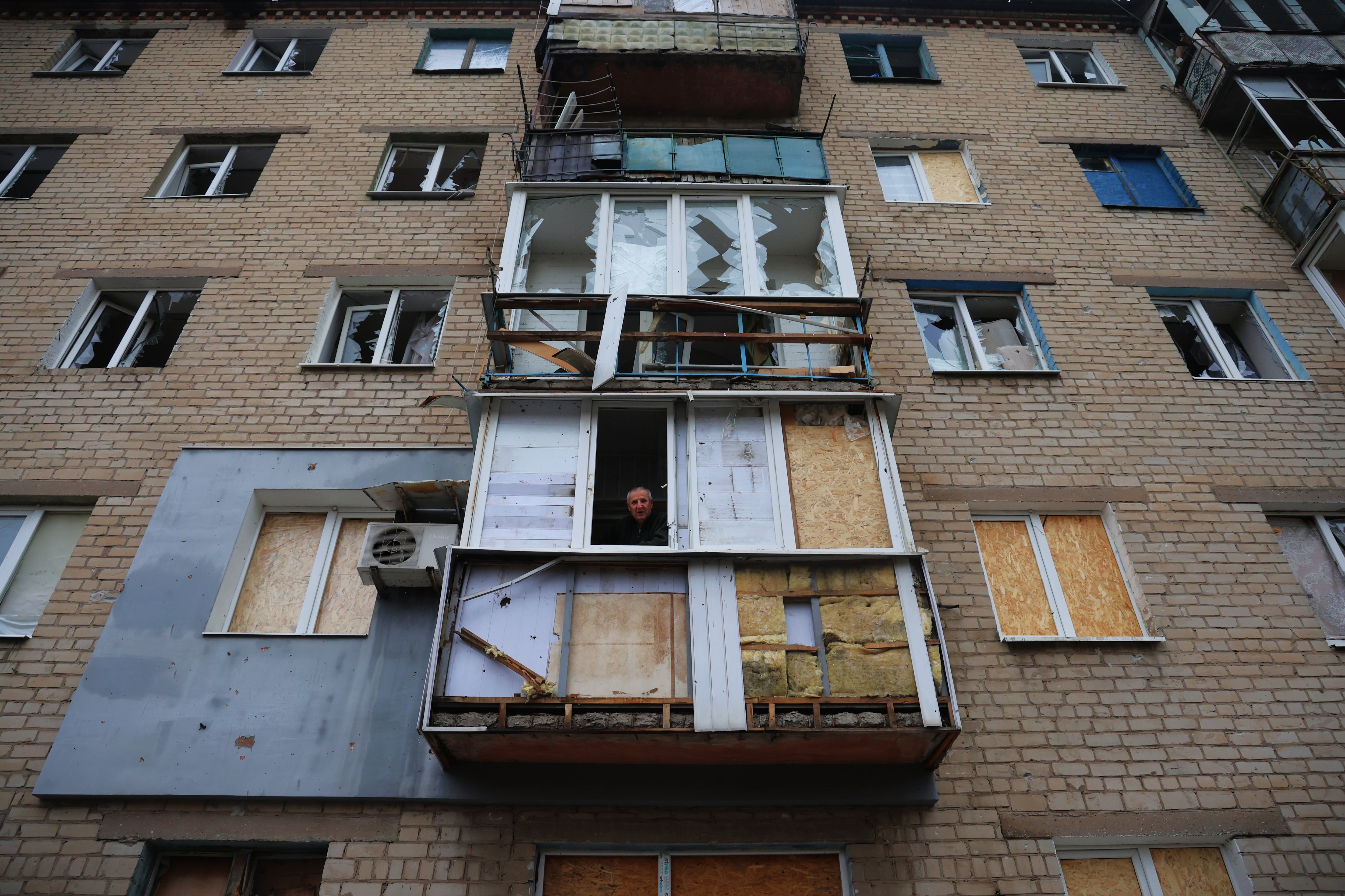 Volodímir, de 77 años, asomado al balcón de su apartamento, con serios daños tras la explosión de una bomba rusa que asesinó ante su edificio el 8 de octubre a 30 personas que iban en dos autobuses.
