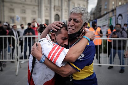 Un aficionado con la camiseta del Boca Juniors y otro con la camiseta del River Plate, se abrazan luego de despedir los restos de Diego Armando Maradona en el velatorio de la capital bonaerense, este jueves en la Plaza de Mayo en Buenos Aires, Argentina.