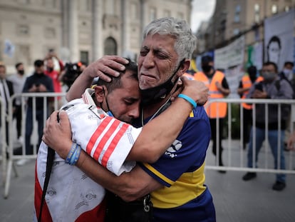 Un aficionado con la camiseta del Boca Juniors y otro con la camiseta del River Plate, se abrazan luego de despedir los restos de Diego Armando Maradona en el velatorio de la capital bonaerense, este jueves en la Plaza de Mayo en Buenos Aires, Argentina.