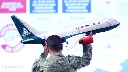 Un soldado del ejercito acomoda una maqueta de un avión de Mexicana durante la conferencia de prensa, en el Palacio Nacional, en Ciudad de México (México).