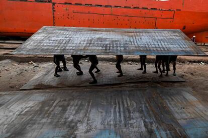 Trabajadores bangladesíes transportan una pesada placa de acero en un astillero junto al río Buriganga, en Dhaka.