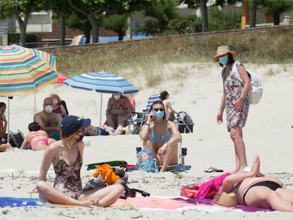 Varias personas protegidas con mascarillas toman el sol en la playa de A Rapadoira, en Foz, en la comarca de A Mariña, Lugo, este jueves.